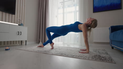 Frau-Führt-Yoga-Übung-Durch-Und-Dehnt-Den-Flexiblen-Körper,-Indem-Sie-Zu-Hause-Die-Hände-Auf-Der-Matte-Hebt.-Sportlerin-Macht-Fitnesstraining-Im-Wohnzimmer-Und-Genießt-Körperliche-Aktivität-Und-Einen-Gesunden-Lebensstil